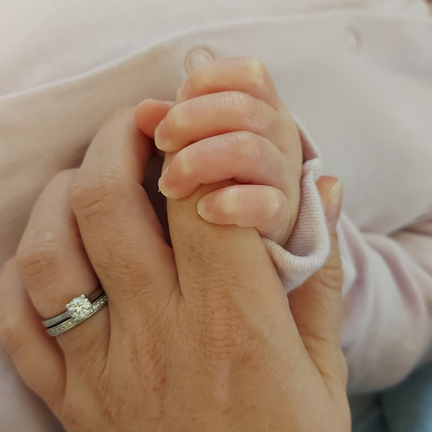 Baby grasping holding onto Mum's hand. Newborn hand and fingers.