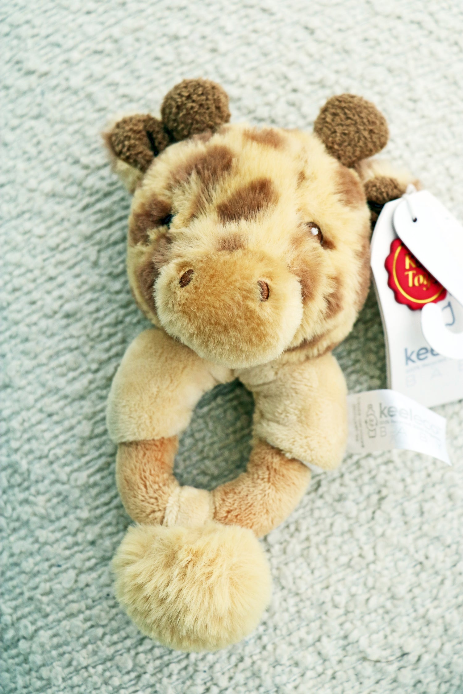 14cm Keeleco Huggy Giraffe Ring Rattle on white background. Newborn toy rattle for babies.