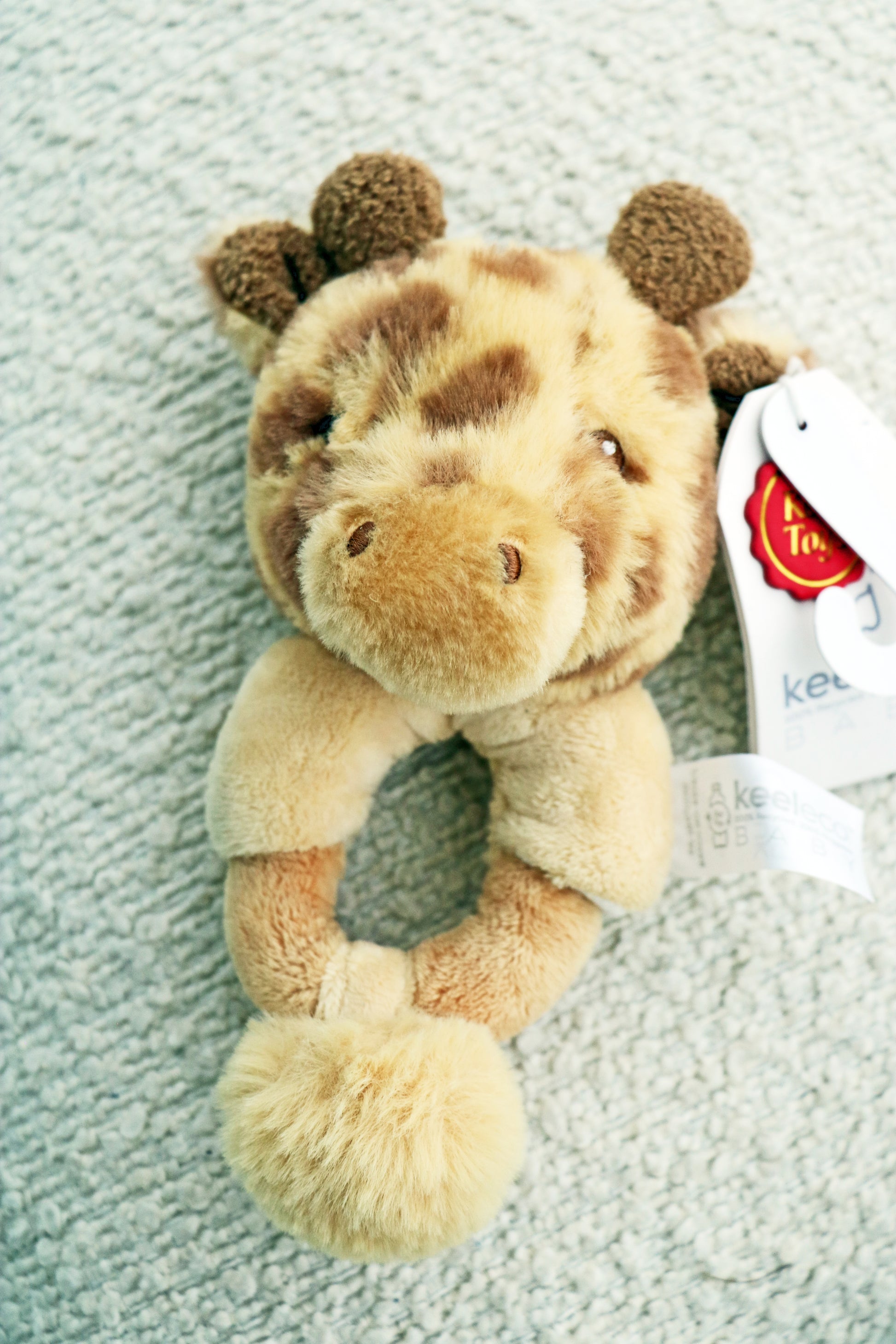 14cm Keeleco Huggy Giraffe Ring Rattle on white background. Newborn toy rattle for babies.