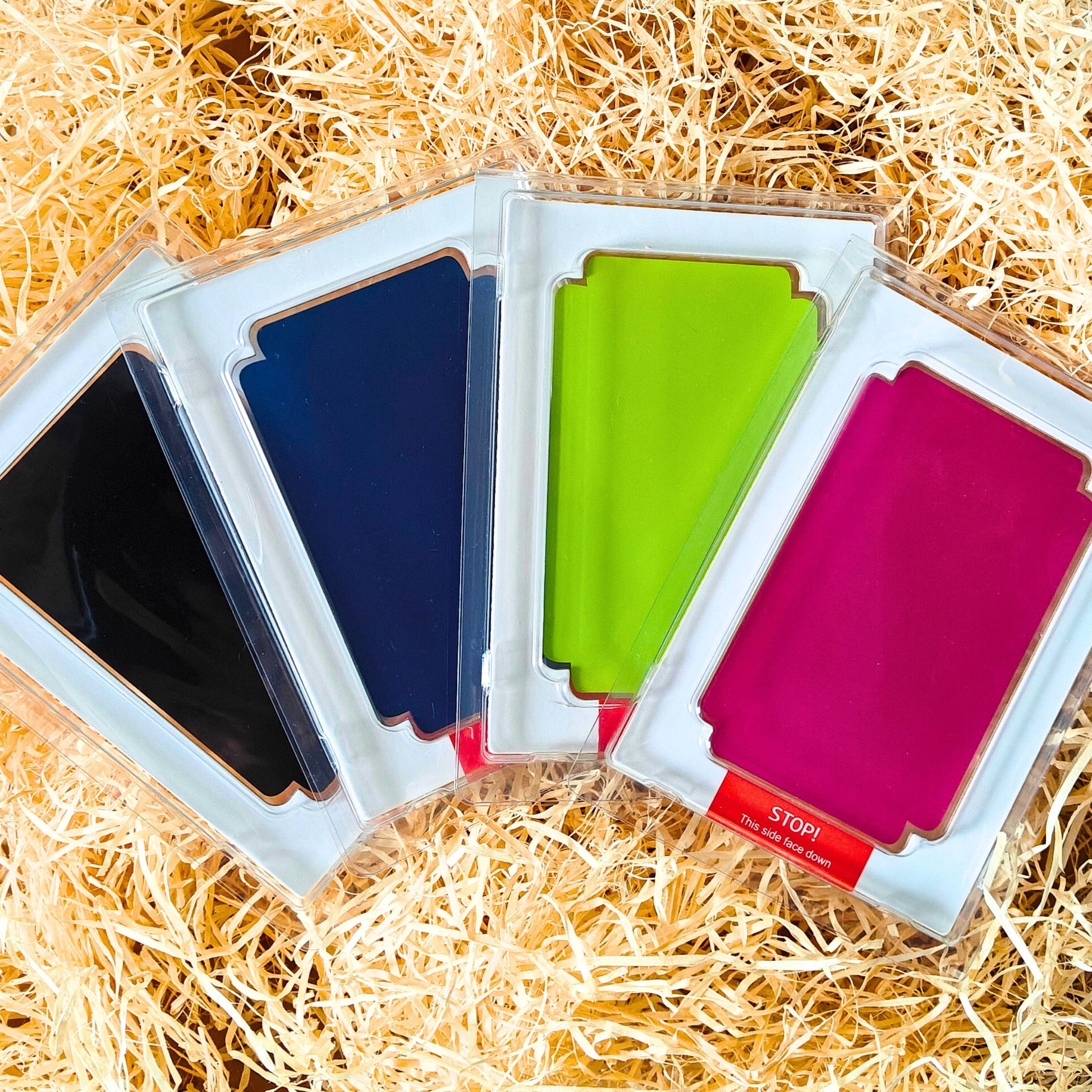 Set of 4 Clean Touch mess free ink pads - Black, Dark Blue, Light Green and Fuchsia for handprints and footprints. On a bed of straw