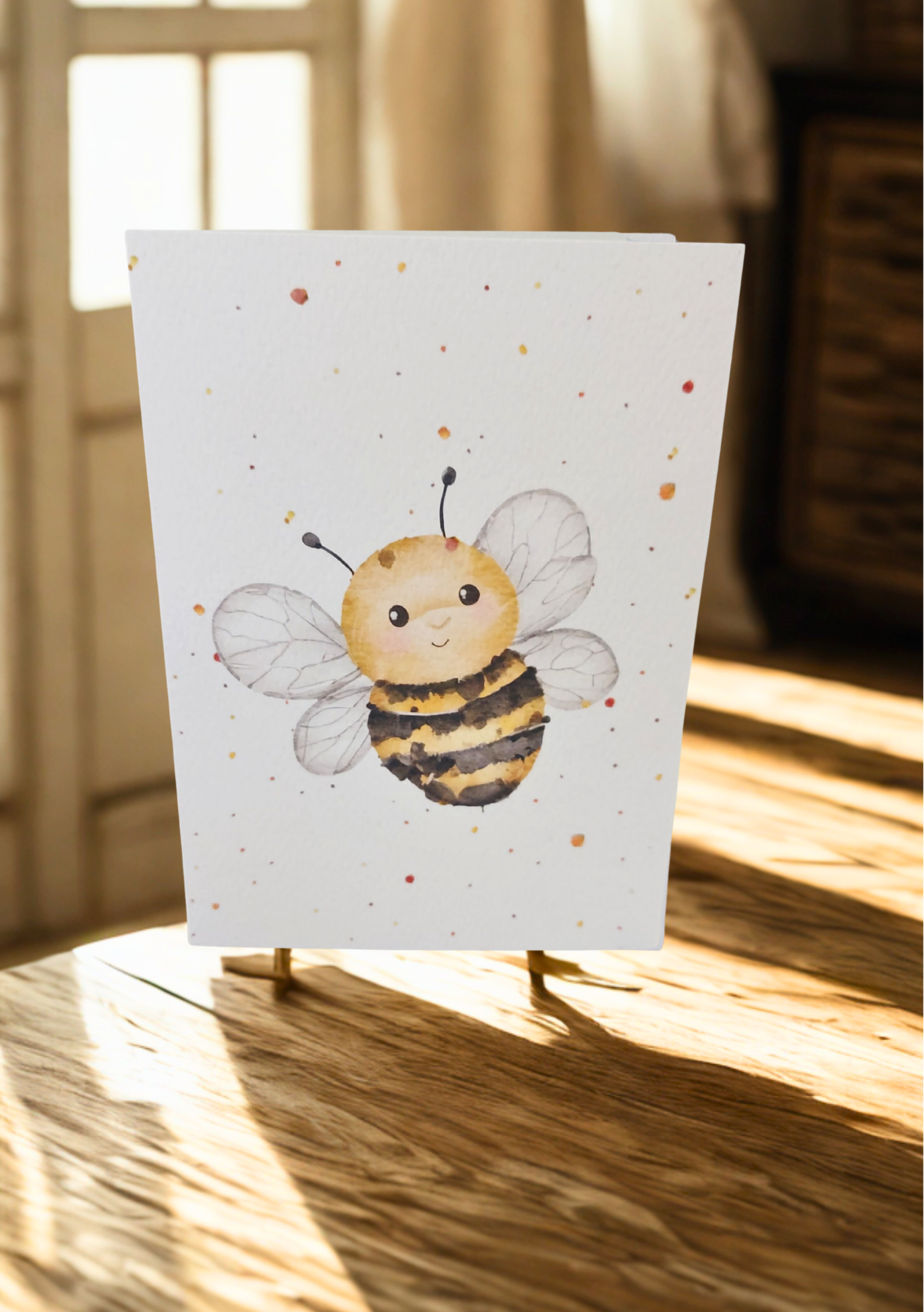 Greetings Card - Watercolour Bee. Blank inside. On wooden table with warm sunlight.