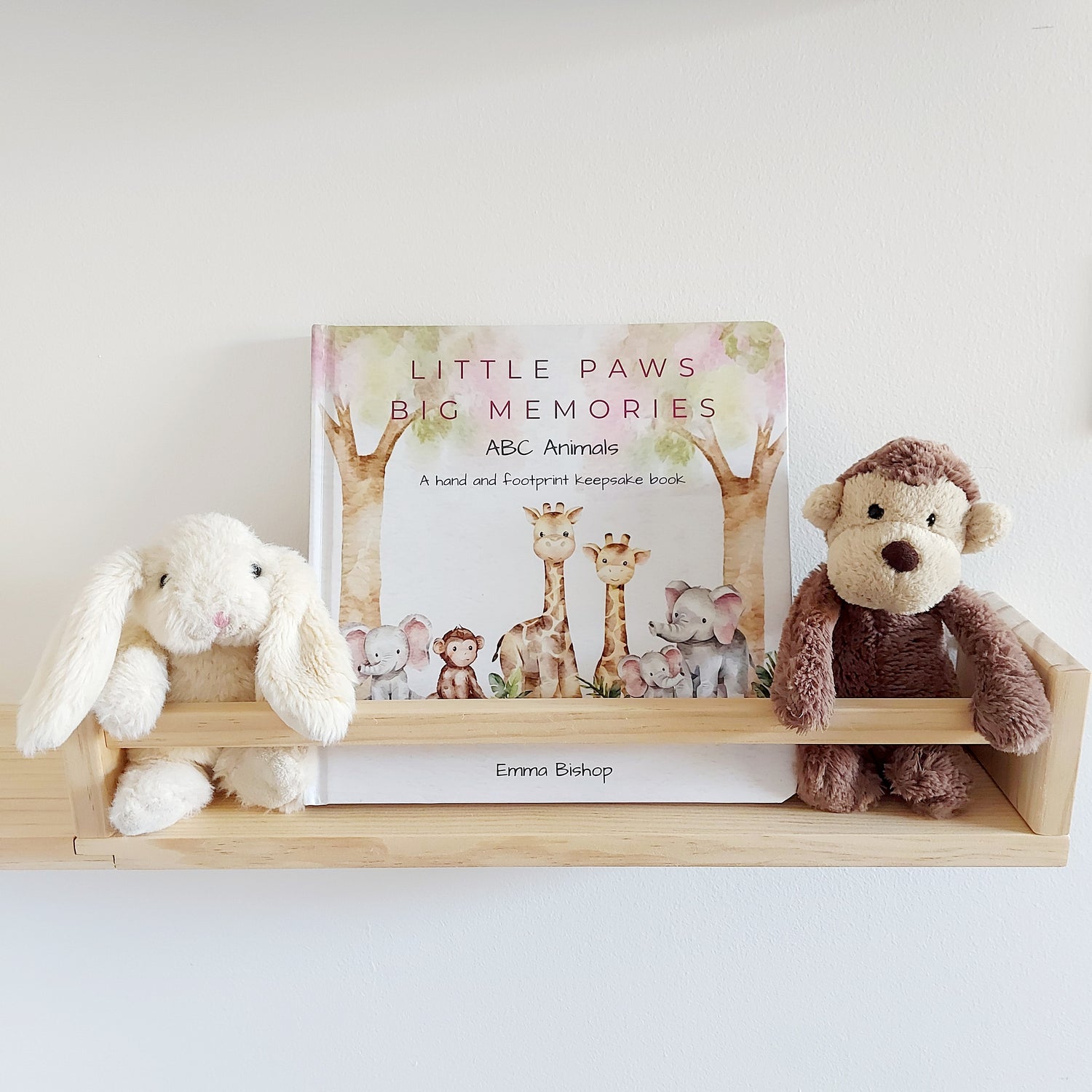 Little Paws Big Memories ABC Animals Baby Hand and Footprint Keepsake Book on a shelf in baby's nursery. Soft toy monkey and rabbit either side of the book. For newborn baby boy or girl, baby shower gift.