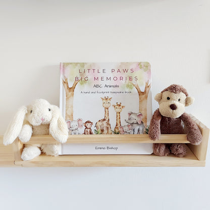 Little Paws Big Memories ABC Animals Baby Hand and Footprint Keepsake Book on a shelf in baby's nursery. Soft toy monkey and rabbit either side of the book. For newborn baby boy or girl, baby shower gift.
