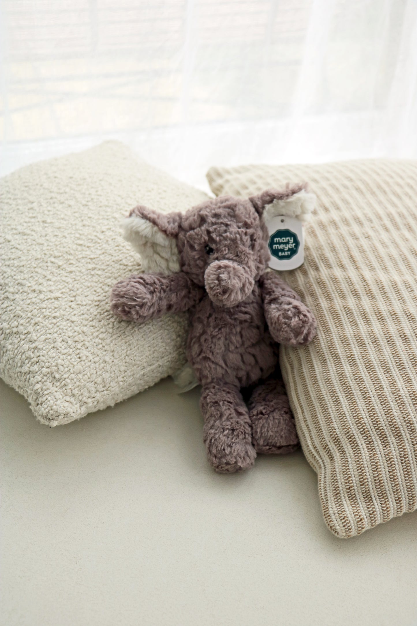 Mary Meyer Putty Elephant soft toy plush for babies and newborn on neutral cushions background