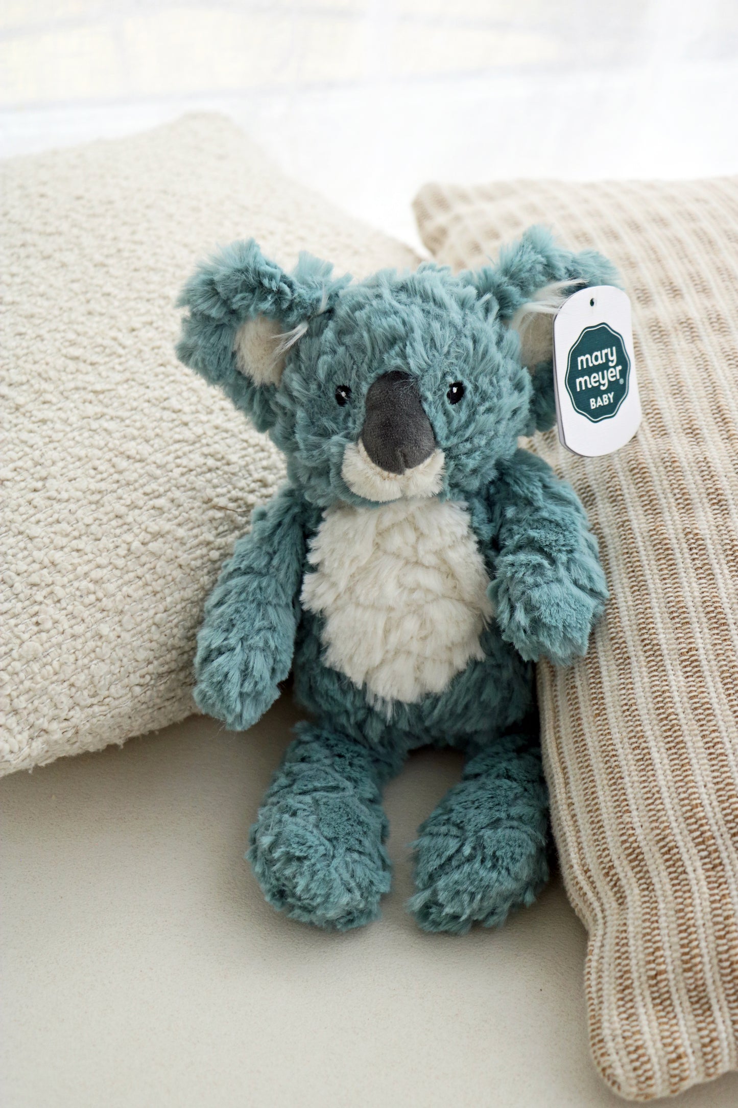 Mary Meyer Putty Koala soft toy plush for babies and newborn on neutral cushions background. mary meyer putty nursery stuffed animal soft toy 11-inches slate blue koala