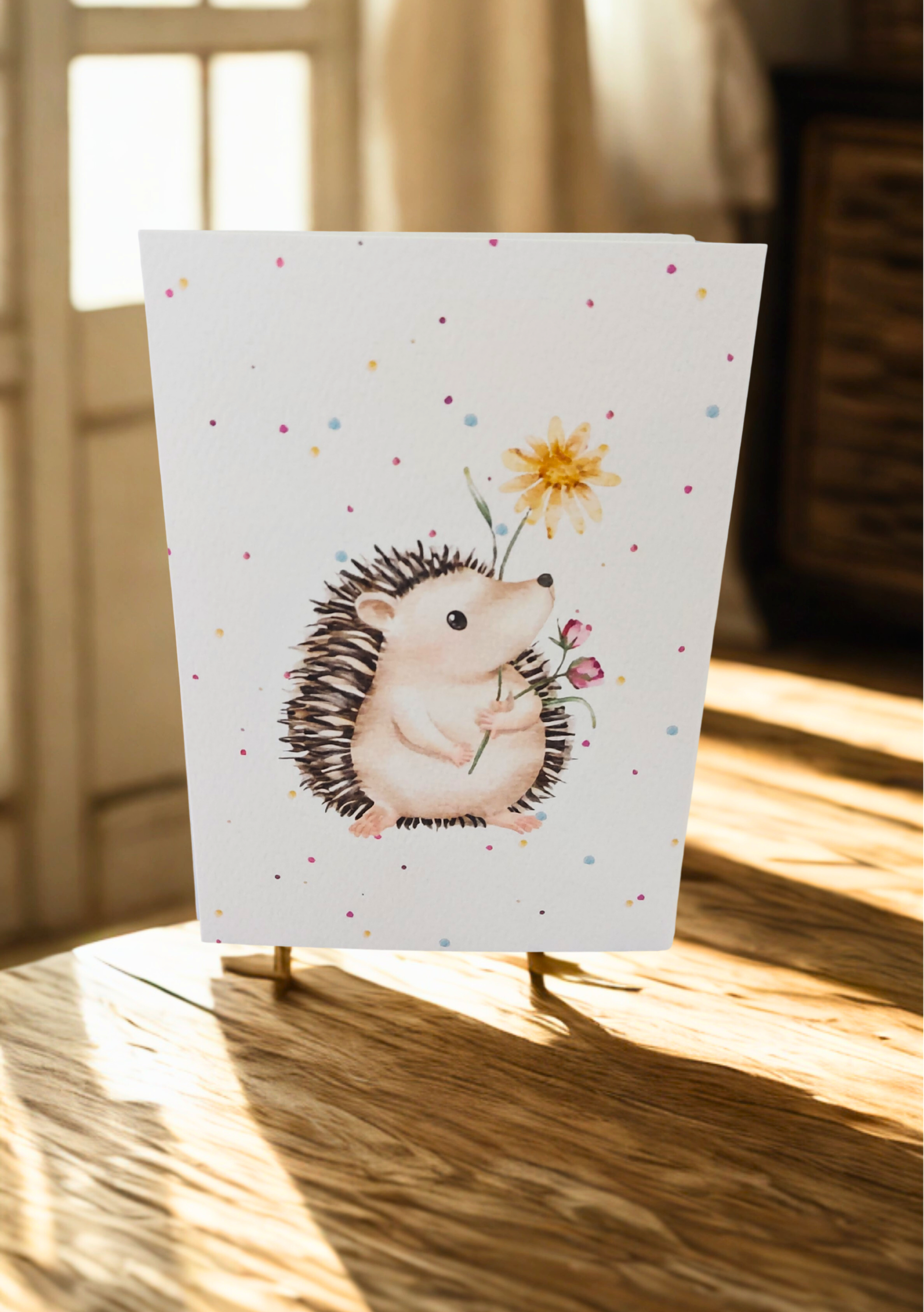Greetings Card - Watercolour Hedgehog. Blank inside. On wooden table with warm sunlight.