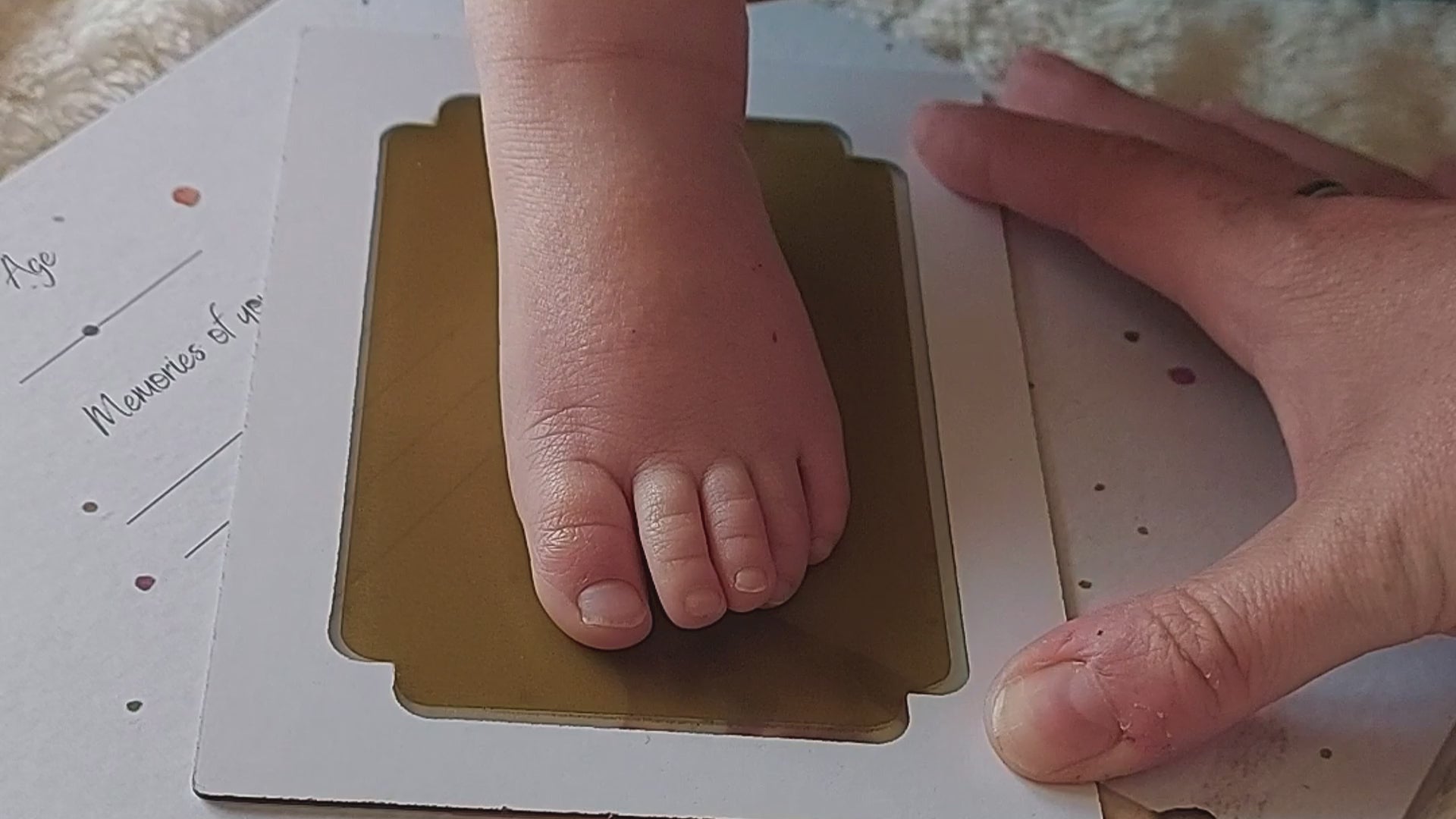 Load video: A video of a new mum taking a footprint and handprint in their hand and footprint memory book. Zooms out to the countryside, showing how quick and easy the prints are to take and can be done anywhere.